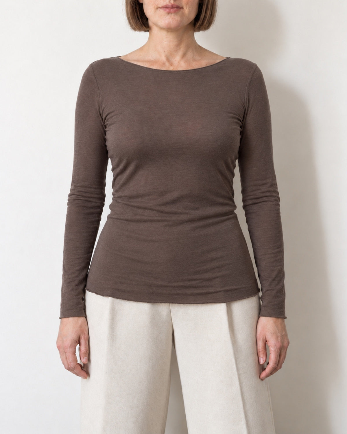 Maglia a manica lunga marrone aderente indossata con pantaloni ecru, vista frontale