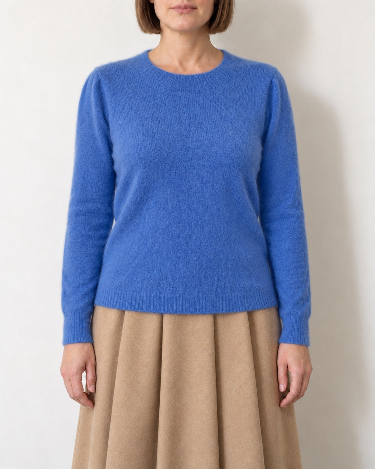 Maglia con maniche a sbuffo azzurra indossata con gonna color cammello, vista frontale