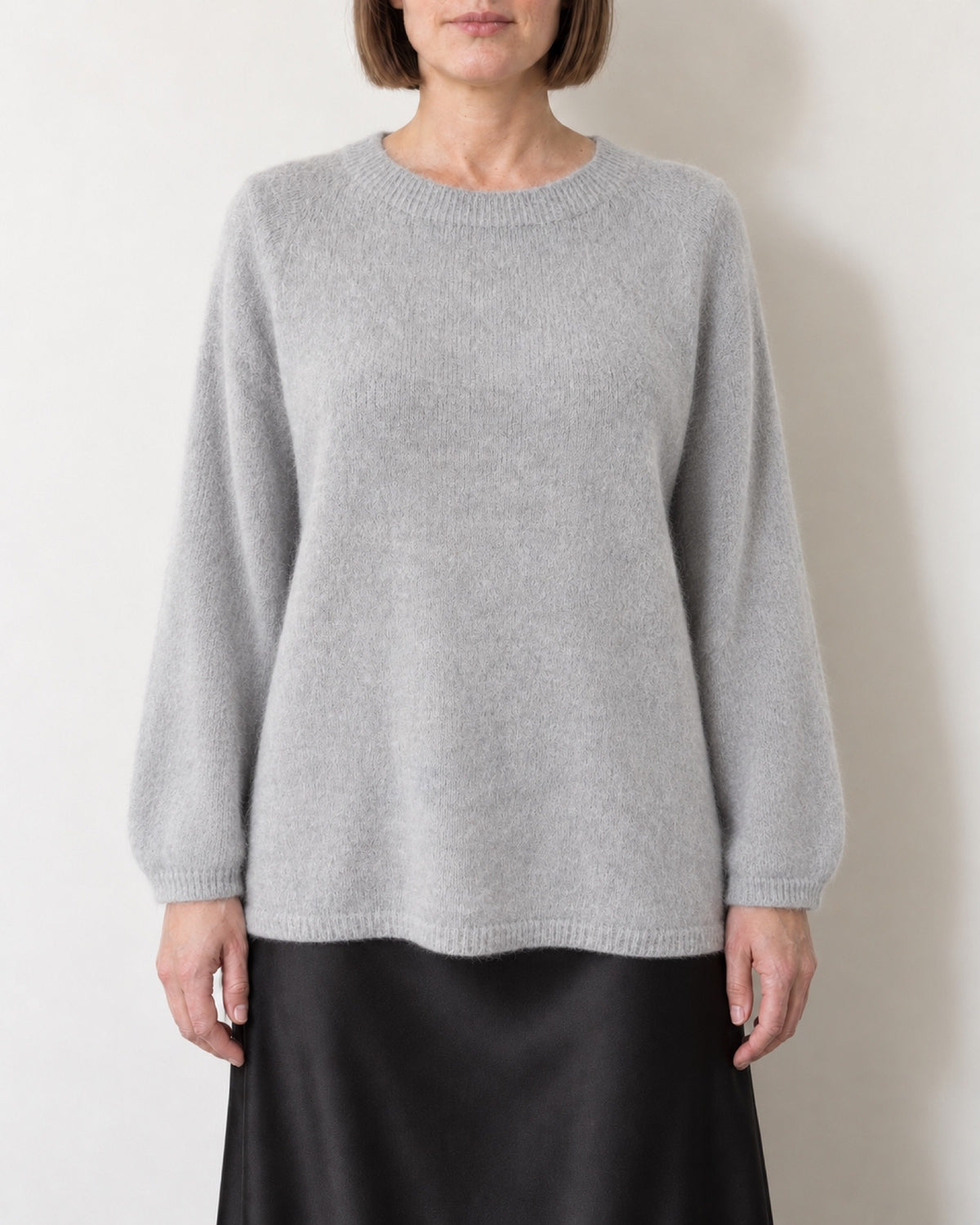 Maglione oversize grigio chiaro indossato con gonna nera in raso, vista frontale