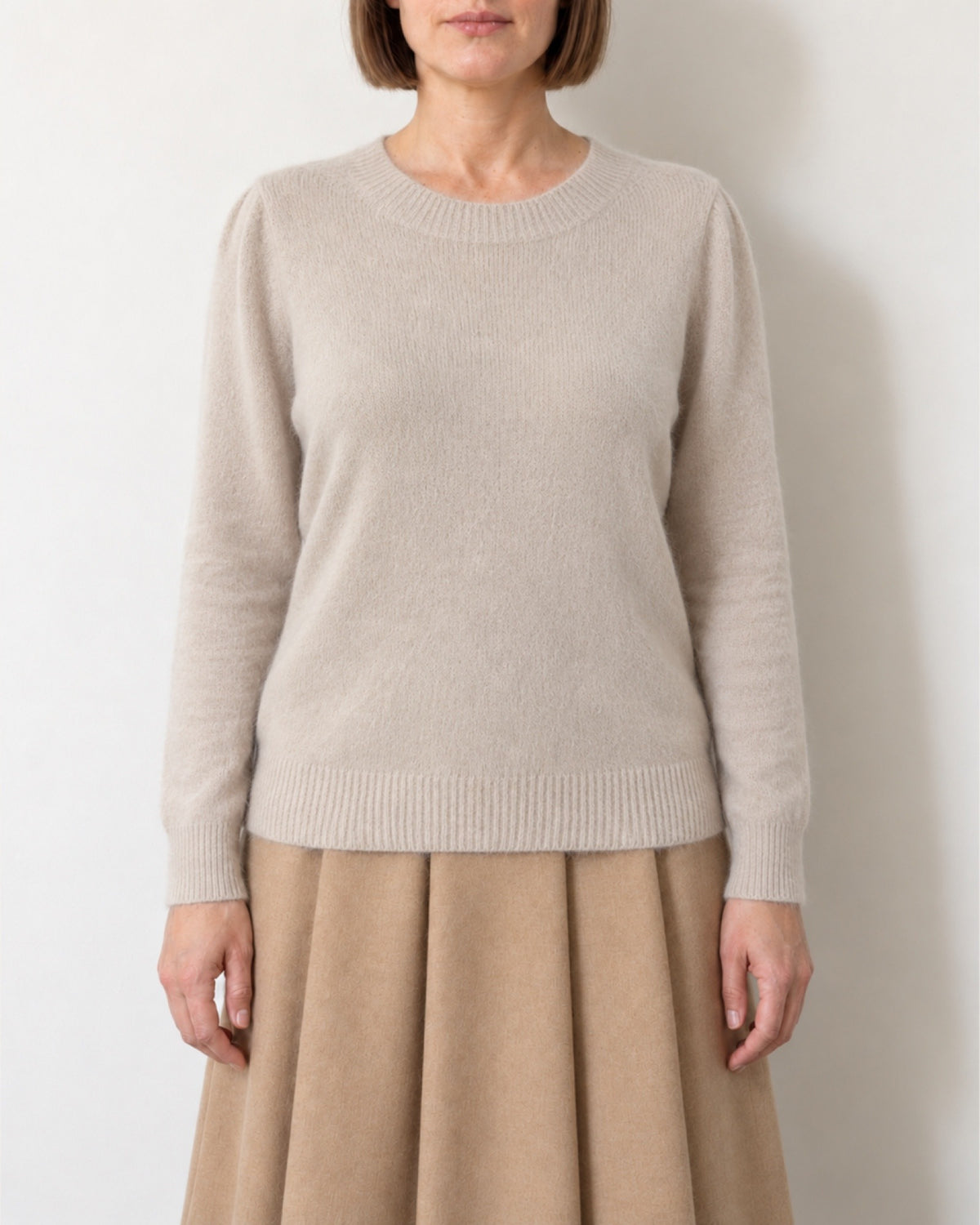 Maglia con maniche a sbuffo beige indossata con gonna color cammello, vista frontale