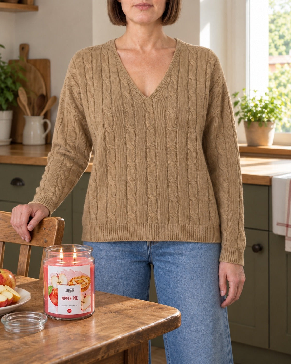 Maglione a trecce cammello con scollo a V indossato con jeans chiari in cucina