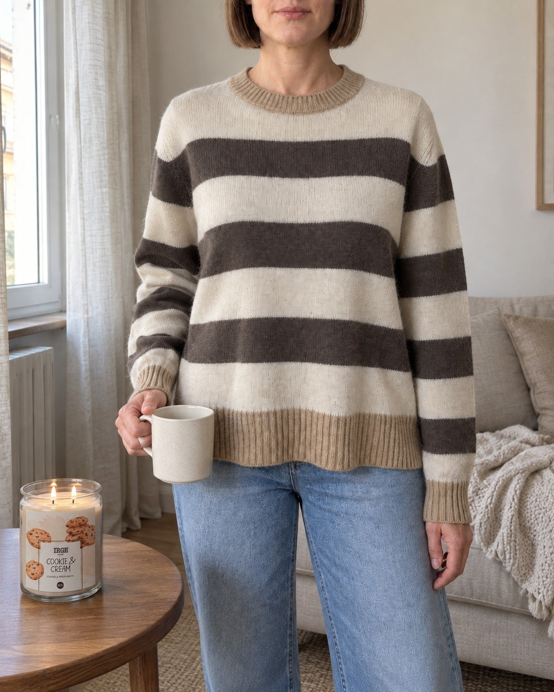 Maglione a righe panna e tortora indossato con jeans chiari in soggiorno
