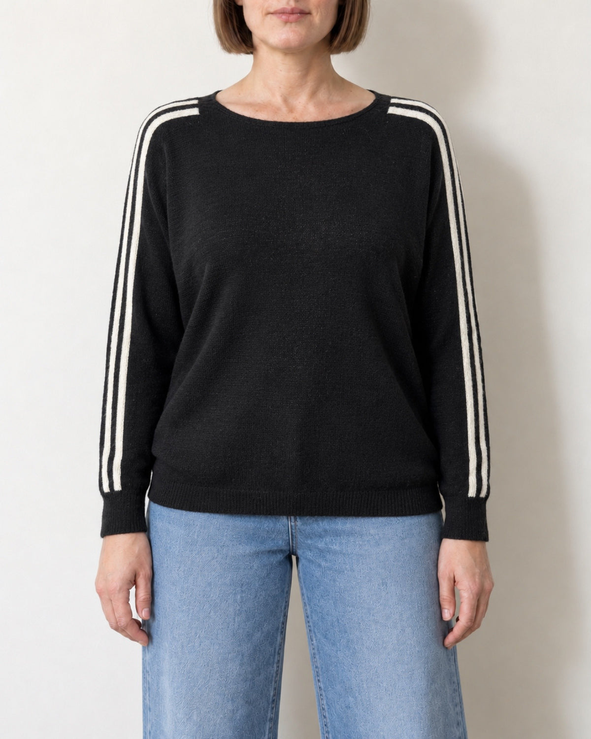 Maglia scollo a barca a pipistrello nera indossata con jeans chiari, vista frontale