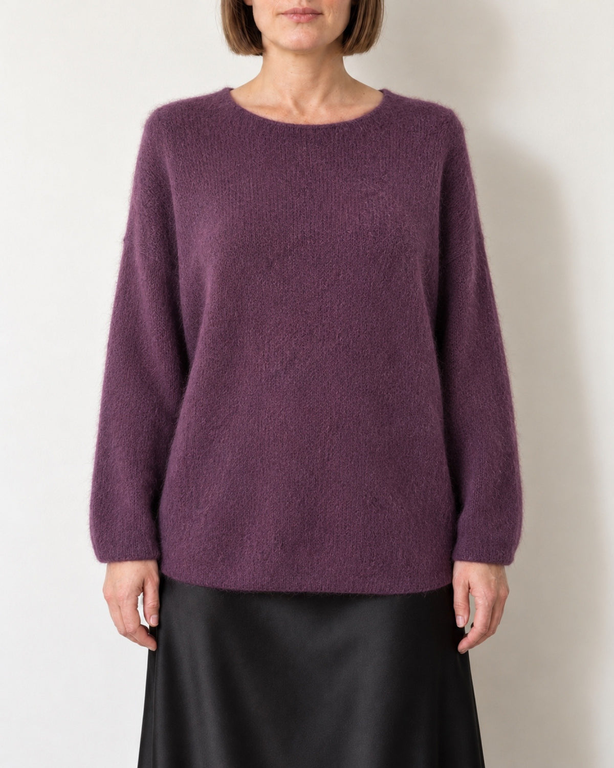 Maglione oversize viola indossato con gonna nera in raso, vista frontale