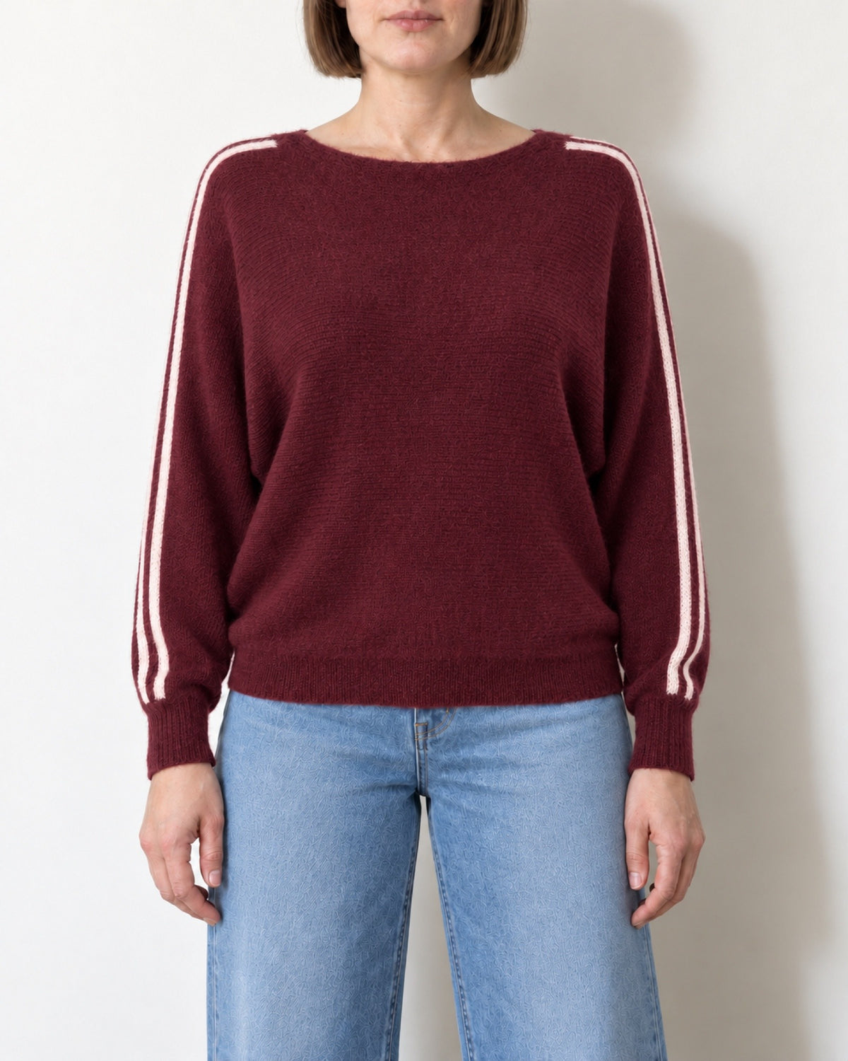 Maglia scollo a barca a pipistrello bordeaux indossata con jeans chiari, vista frontale
