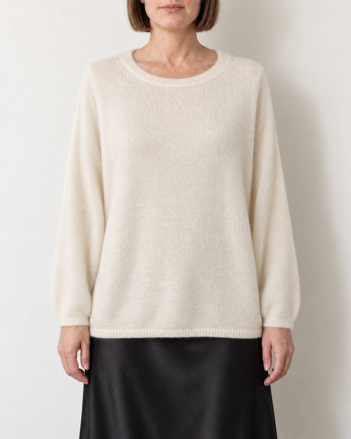 Maglione oversize panna indossato con gonna nera in raso, vista frontale