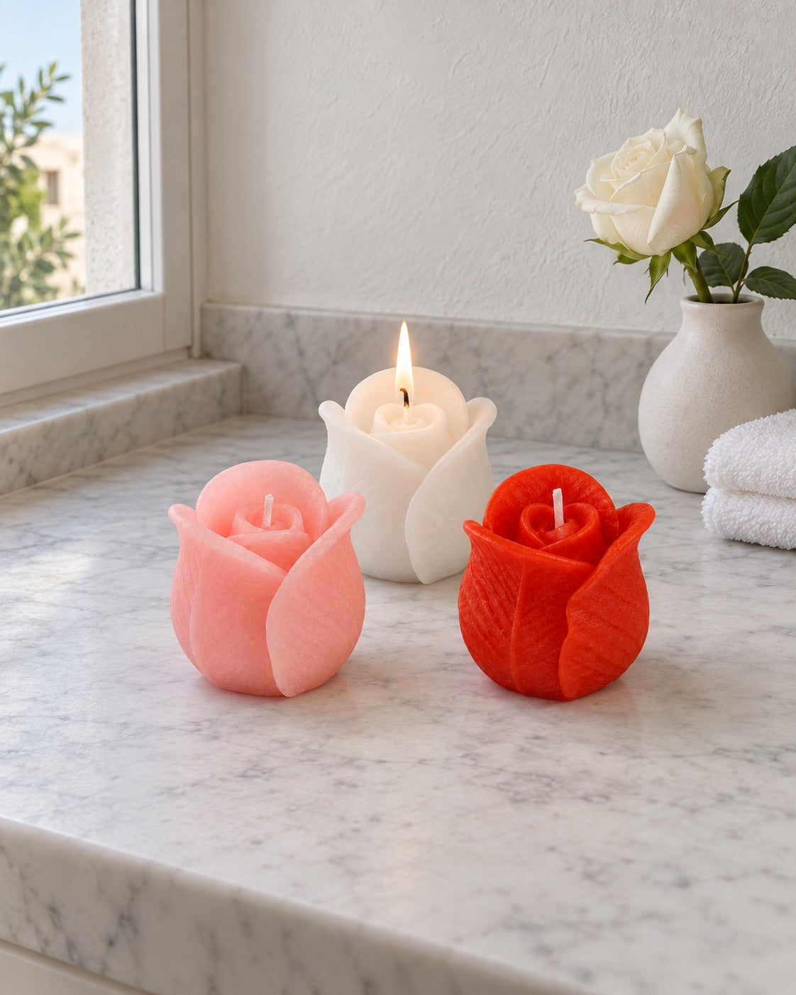 Set di tre candele a forma di rosa su mensola in marmo, con asciugamano