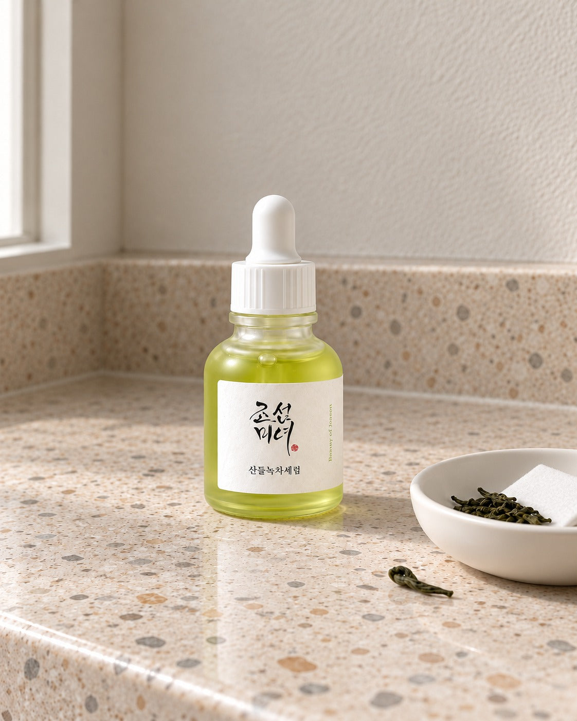 Siero al tè verde Beauty of Joseon su lavabo in terrazzo, con foglie di tè