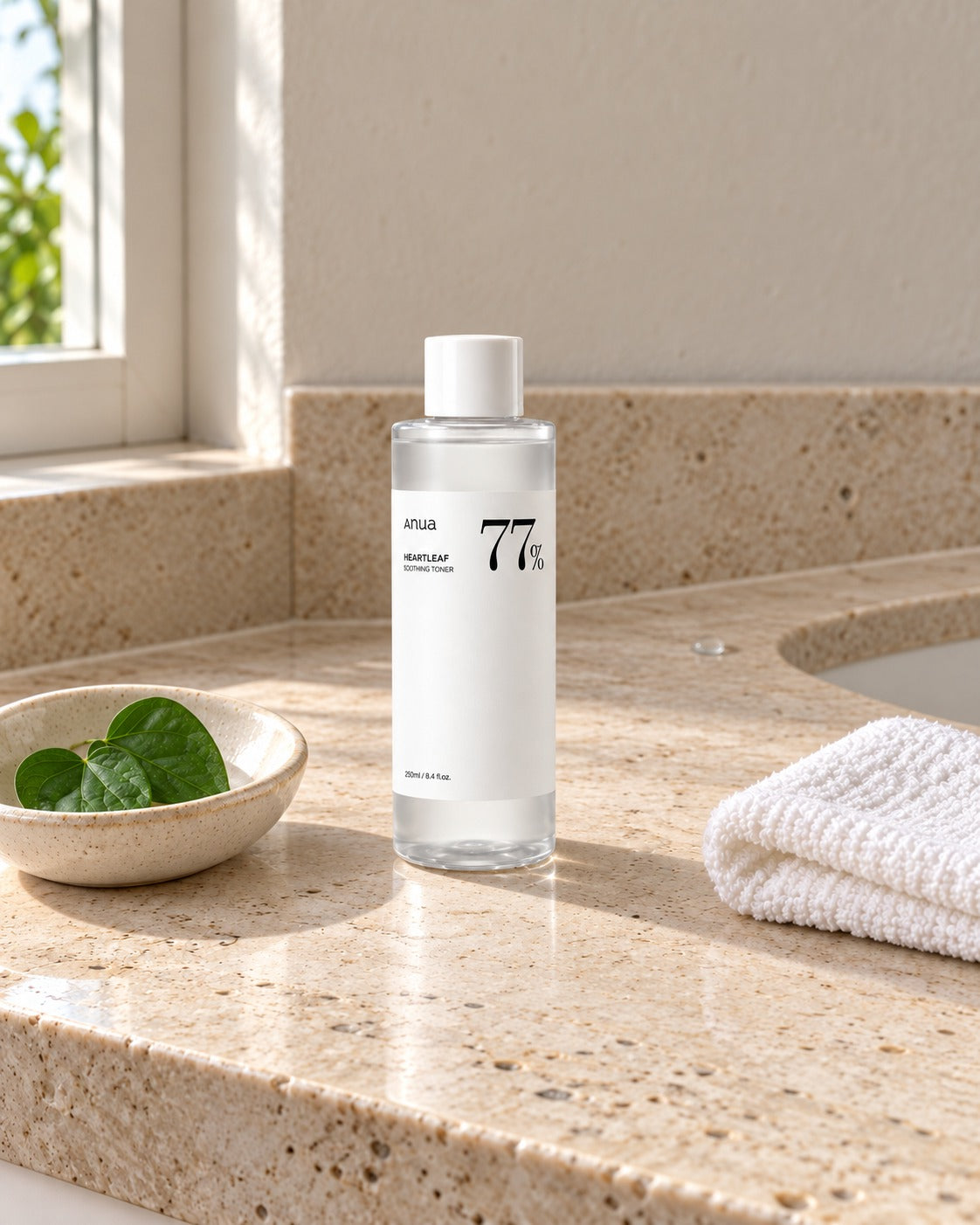 Tonico Anua Heartleaf 77 su lavabo in travertino, con panno piegato