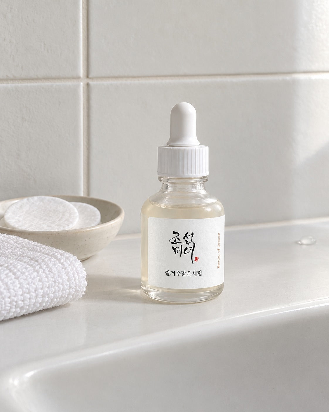 Siero Glow Deep Beauty of Joseon su lavabo in ceramica bianca, con panno e dischetti