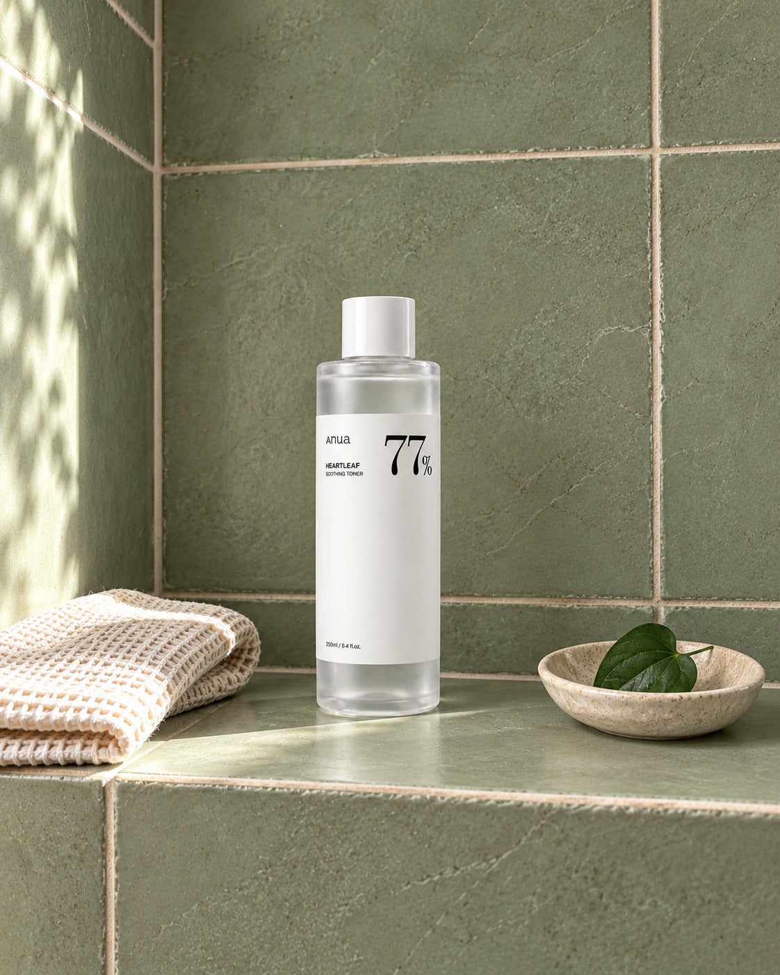 Tonico Anua Heartleaf 77 in una nicchia verde salvia del bagno, con asciugamano