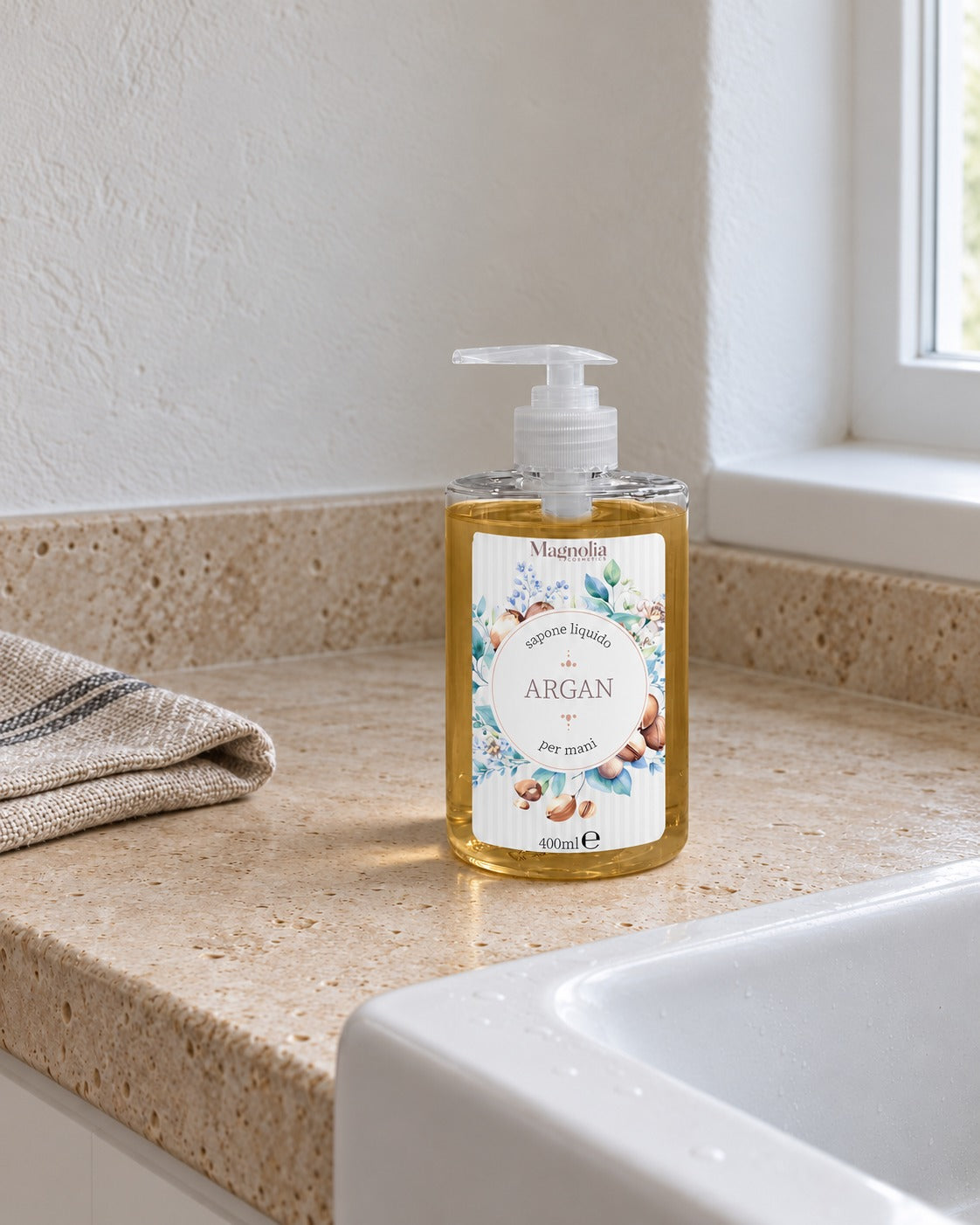 Sapone liquido per mani su piano in travertino accanto al lavello, con panno di lino