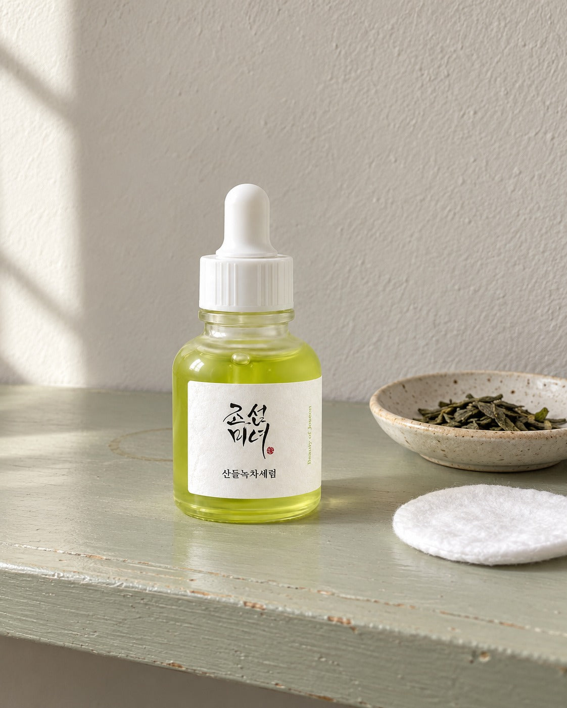 Siero al tè verde Beauty of Joseon su mensola verde salvia, con dischetto di cotone